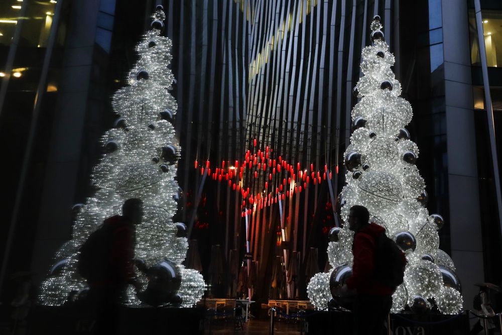 A man is reflected in a window as he walks past a Christmas tree in London, Thursday, December 3, 2020. (AP Photo)