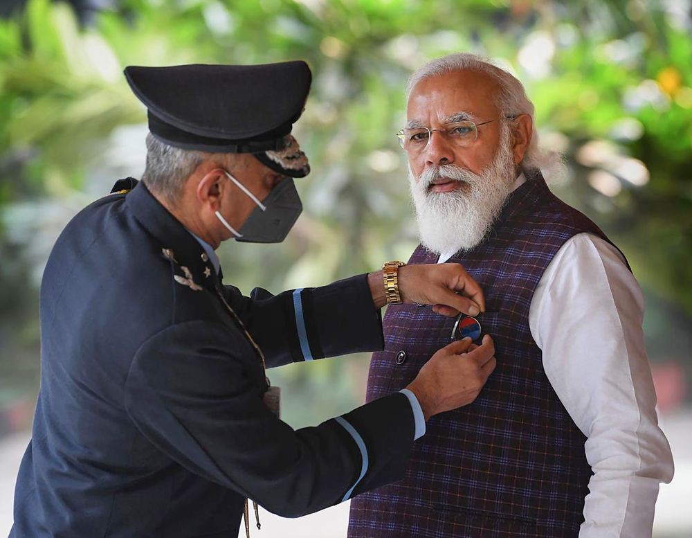 New Delhi: A Kendriya Sainik Board official pins a flag to Prime Minister Narendra Modi on the occasion of Armed Forces Flag Day. (PTI Photo)