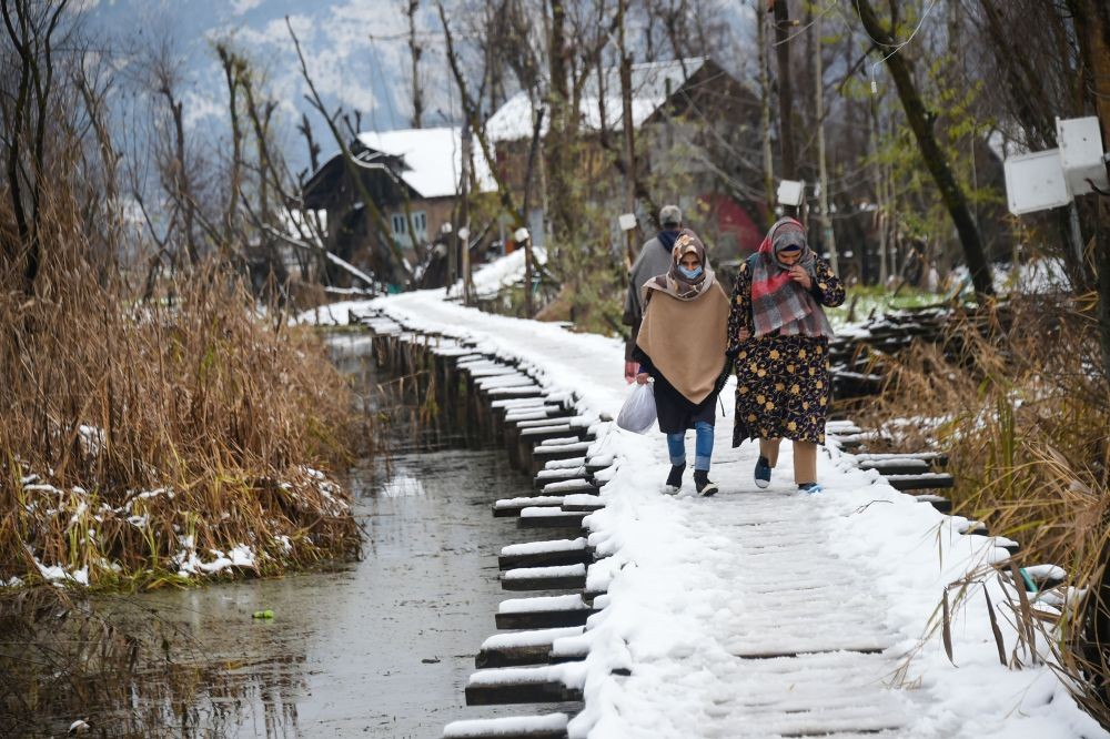 Srinagar: People walk on a snow covered bridge after the town received fresh snowfall, in Srinagar, Saturday, Dec. 12, 2020. (PTI Photo/S. Irfan)