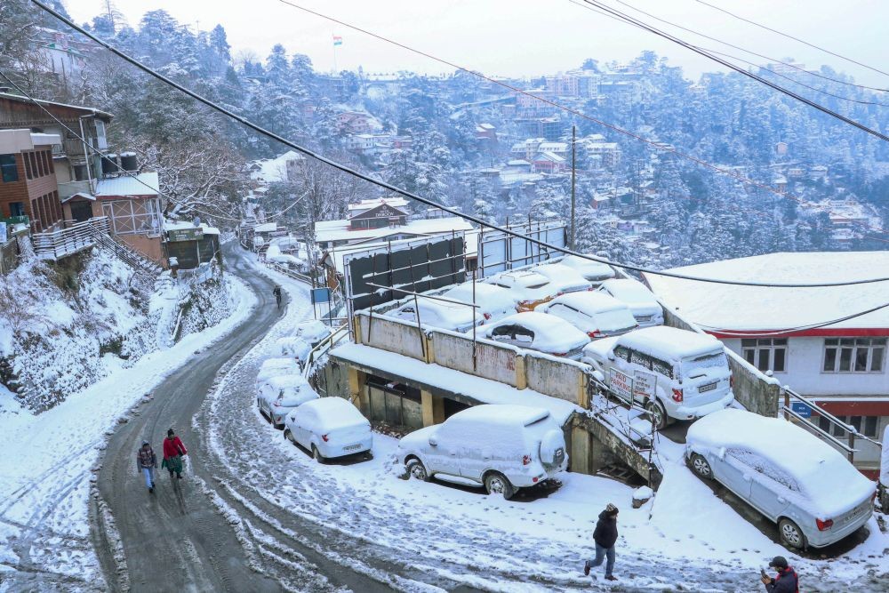 Shimla: People walk on a snow covered road after fresh snowfall in Shimla, Monday, Dec. 28, 2020. (PTI Photo)