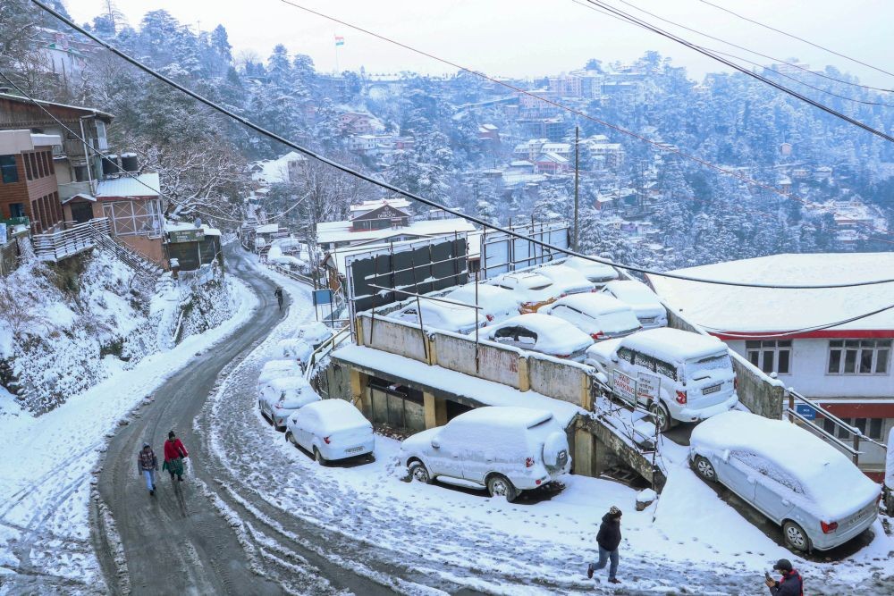 Shimla: People walk on a snow covered road after fresh snowfall in Shimla, Monday, Dec. 28, 2020. (PTI Photo)