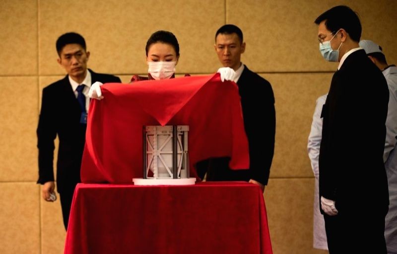 A staff member covers the container of lunar samples with a veil during the Chang'e-5 Lunar Samples Handover Ceremony at China National Space Administration in Beijing, capital of China on December 19, 2020. (IANS Photo)