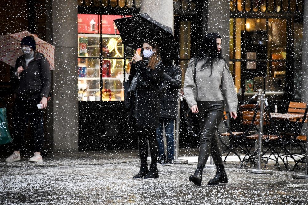 A woman wearing a face mask takes a photo on her phone in Covent Garden, London, Thursday, December 3, 2020.  (AP Photo)