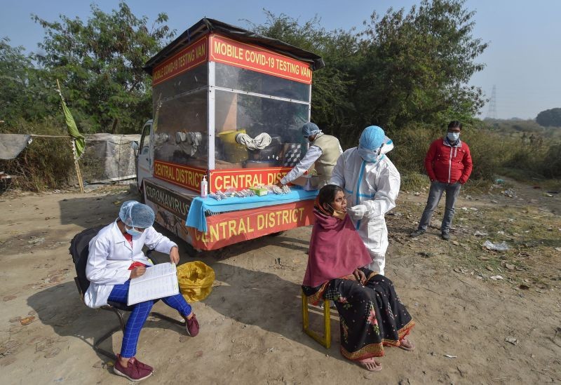 A health worker, wearing protective gear, collects swab sample for COVD-19 testing at Baila Gaon Jhuggi Basti in New Delhi on December 15. (PTI Photo)