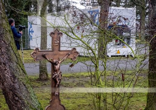 A cross is seen near a refrigeration container storing Covid-19 victims on the cemetery in Hanau near Frankfurt, Germany, Thursday, Dec. 17, 2020. (AP Photo/Michael Probst)
