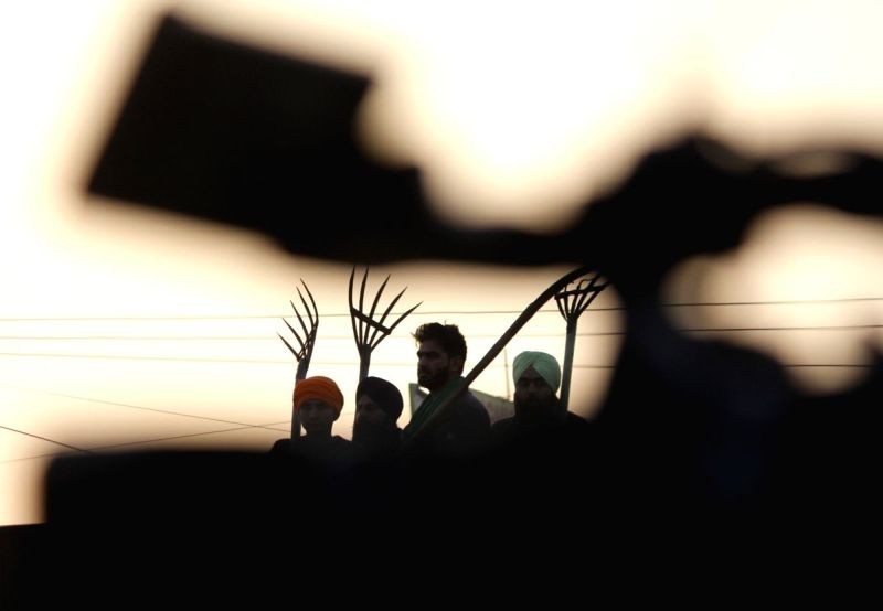 Farmers during sunset, on the 19th day of their ongoing protest against the Centre's new farm laws, at Delhi-Haryana's Singhu Border on December 14. (IANS Photo)