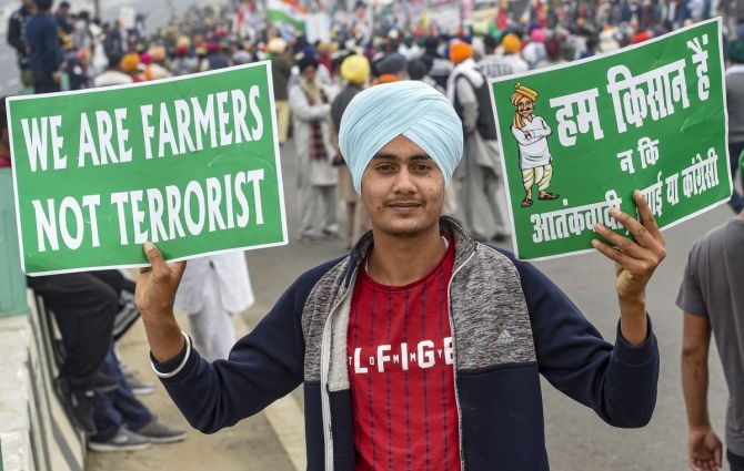 A farmer holds placards during a protest march against Centres agri-laws, at the Delhi-Meerut Expressway in New Delhi. Photograph: Kamal Singh/PTI Photo