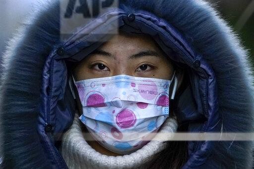 A woman wearing a face mask to help curb the spread of the coronavirus walks on a street during the morning rush hour in Beijing, Wednesday, Dec. 16, 2020. (AP Photo/Andy Wong)