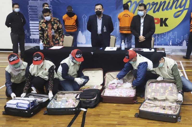 Officers arrange suitcases full of rupiah and U.S. dollar bills confiscated from suspects as Chairman of Indonesia's Corruption Eradication Commission Firli Bahuri, top center, looks on during a news conference on a corruption case involving government's COVID-19 pandemic aid distribution, in Jakarta, Indonesia, Sunday, Dec. 6, 2020. Indonesian Social Affairs Minister Juliari Batubara turned himself in to anti-corruption authorities Sunday to face charges of taking bribes in the procurement of goods to be distributed to the poor as COVID-19 social assistance packages. (AP/PTI Photo)