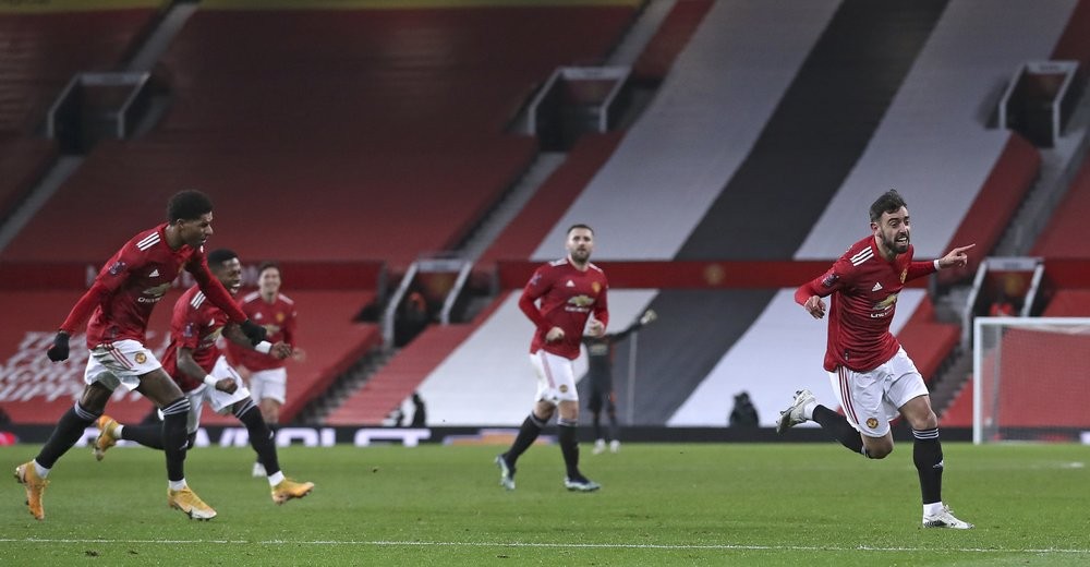 Manchester United's Bruno Fernandes, right, celebrates scoring his side's third goal during the English FA Cup 4th round soccer match between Manchester United and Liverpool at Old Trafford in Manchester, England, Sunday, Jan. 24, 2021. (Martin Rickett/Pool via AP)