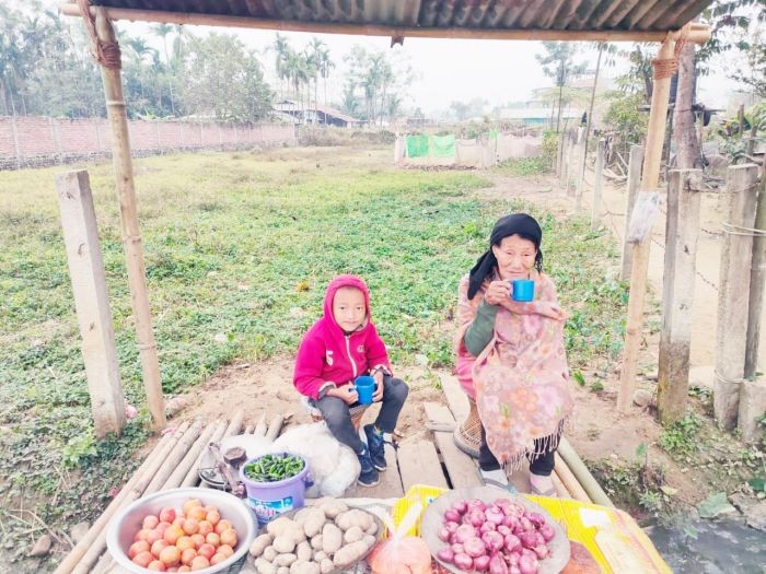A grandmother along with her grandson sips tea as they try to sell vegetables in a makeshift shop on an early morning in Dimapur. (Morung Photo)