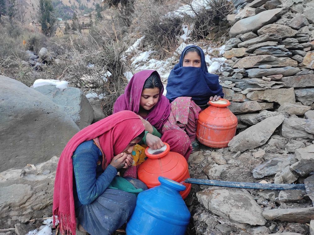 Doda: Young women collect water from a pipe connected to a sea body, owing to the absence of piped water supply in the area, at Thanwala village in Bhaderwah of Doda District, Sunday, Jan. 24, 2021. (PTI Photo)