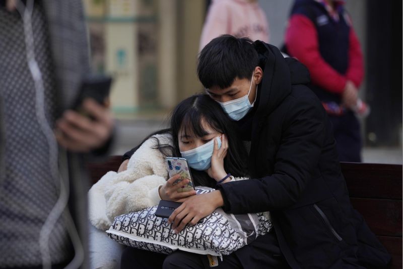 A man and woman wearing masks to help protect themselves from the coronavirus share a smartphone on the street in Wuhan in central China s Hubei province on January 14, 2021. A global team of researchers for the World Health Organization arrived Thursday in the Chinese city where the coronavirus pandemic was first detected to conduct a politically sensitive investigation into its origins amid uncertainty about whether Beijing might try to prevent embarrassing discoveries. (AP/PTI Photo)