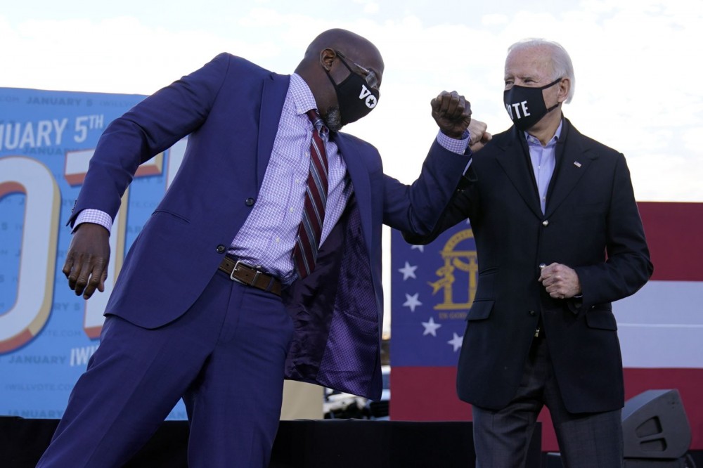 The then Democratic Senate candidate Raphael Warnock elbow bumps with President-elect Joe Biden during a campaign rally in Atlanta on January 4, Biden campaigns for Senate candidates Warnock and Jon Ossoff. (AP/PTI File Photo)