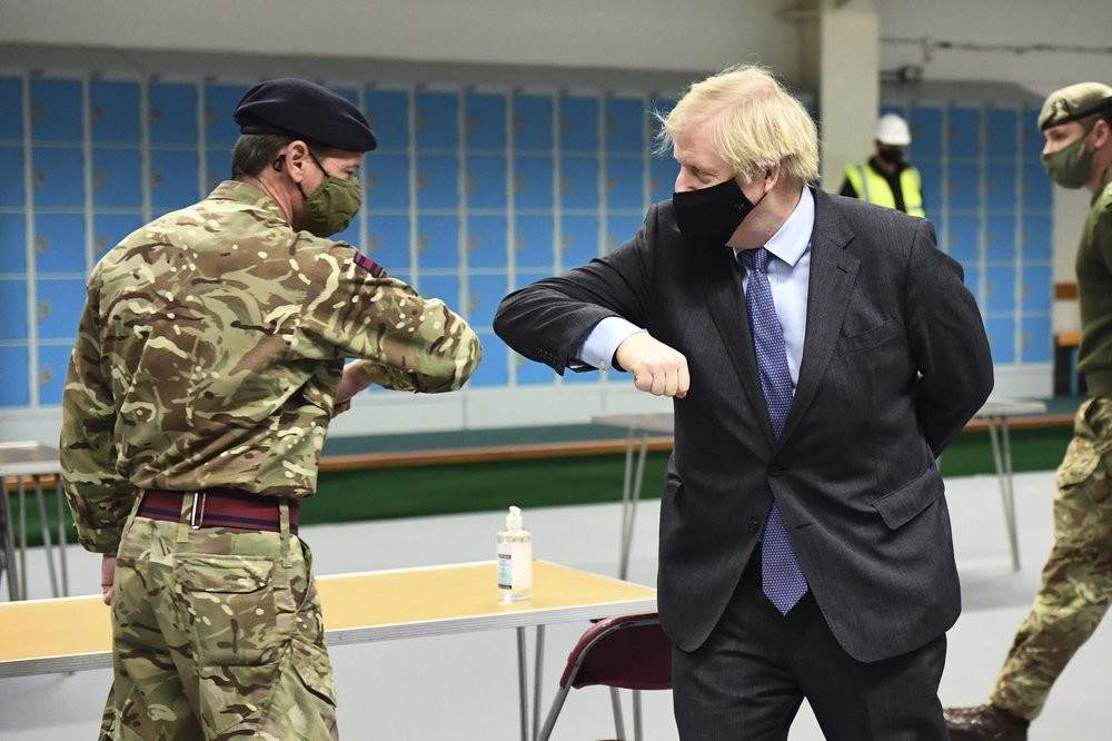 Britain's Prime Minister Boris Johnson elbow bumps a member of the military as he meets troops setting up a vaccination centre in the Castlemilk district of Glasgow, on his one day visit to Scotland on January 28. (AP Photo)