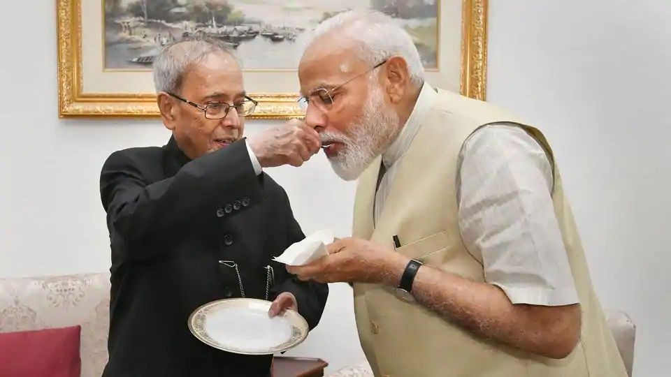 In the photographs accompanying the tweet, Pranab Mukherjee, known for his reserved, even stern demeanour was seen offering sweets to PM Modi, in the traditional Indian way of felicitation or celebration. (PTI PHOTO.)