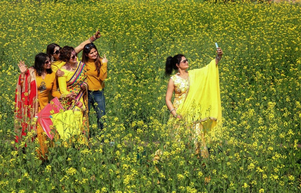Patiala: Youngsters get a selfie clicked in a mustard field on the occasion of Basant Panchami festival, which marks the arrival of Spring season, in Patiala district, Monday, Feb. 15, 2021. (PTI Photo)