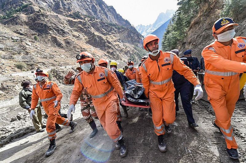 NDRF personnel carry the body of a victim who died in the massive floods caused after a glacier broke off in Joshimath in the Dhauli Ganga river, near Raini village in Chamoli district of Uttarakhand on February 9, 2021. (PTI Photo)