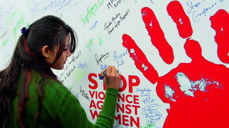 A student signs a poster to raise the issue of violence against women on the occasion of International Women's Day at the University of Jammu. (Photo: PTI)