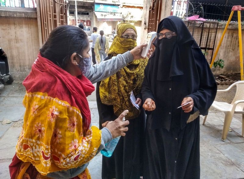 A voter undergoes thermal scanning at a polling station during the civic body election in Ahmedabad on February 21, 2021. (PTI Photo)