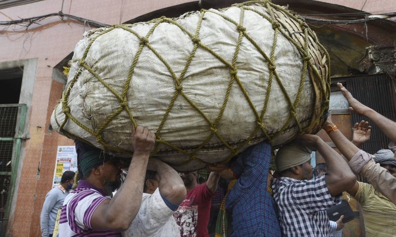 Workers carry a basket of vegetables on their heads at a wholesale market, in Kolkata, Monday, Feb. 1, 2021. (PTI Photo/Ashok Bhaumik)