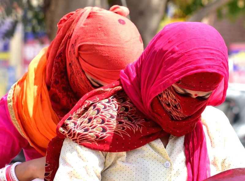 Women cover their faces to avoid scorching sun on a hot day. (IANS File Photo)