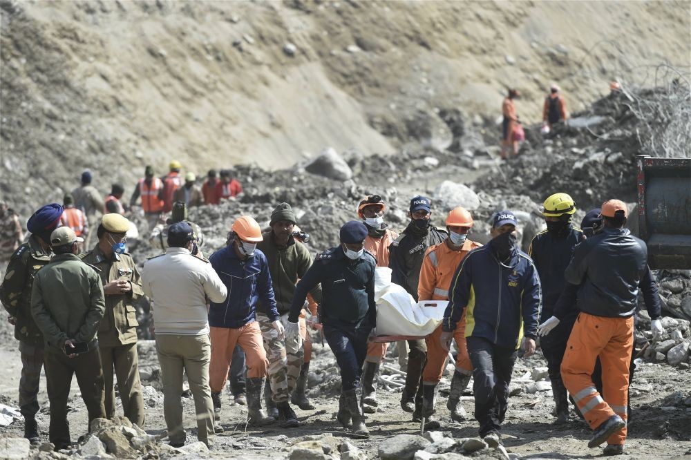 Chamoli: NDRF personnel carry the mortal remains of a flash flood victim near Raini village, in the aftermath of a glacier burst in Uttarakhand's Joshimath that triggered the flood in Chamoli district, Sunday, Feb. 14, 2021. (PTI Photo/Arun Sharma)