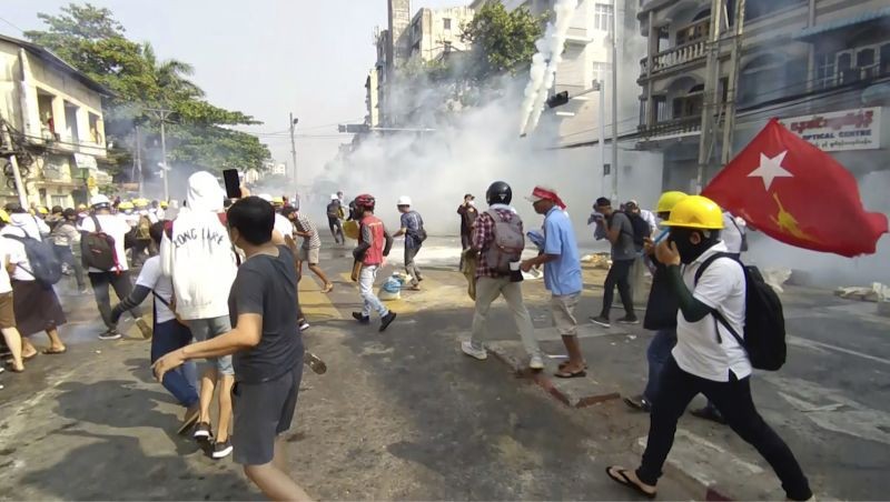 In this image from a video, anti-coup protesters react as smoke from tear gas rises in Yangon, Myanmar on February 28, 2021. Police fired tear gas and water cannons and there were reports of gunfire Sunday in Myanmar's largest city where another anti-coup protest was underway with scores of students and other demonstrators hauled away in police trucks. (AP/PTI Photo)