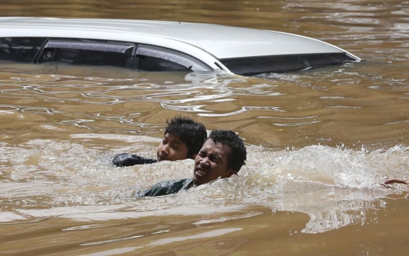 Jakarta : People swim through a flooded neighborhood following heavy rains in Jakarta, Indonesia, Saturday, Feb. 20, 2021. Heavy downpours combined with poor city sewage planning often causes heavy flooding in parts of greater Jakarta. AP/PTI