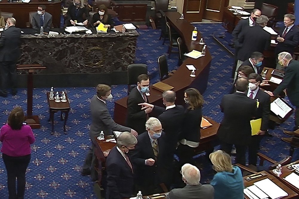 In this image from video, Senate Minority Leader Mitch McConnell of Ky., lower center right, and other Republican senators and staff talk on the floor after a vote on the motion to allow witnesses in the second impeachment trial of former President Donald Trump in the Senate at the U.S. Capitol in Washington, Saturday, Feb. 13, 2021. (Senate Television via AP)