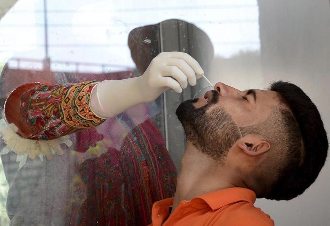A medic collects swab sample of a man for COVID-19 test at Civil Hospital, amid concern over surge in COVID-19 cases, in Amritsar, on Saturday. Photograph: PTI Photo