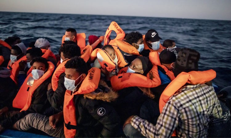 Migrants and refugees wait for assistance from aid workers on an overcrowded rubber boat in the Mediterranean Sea. File/AP