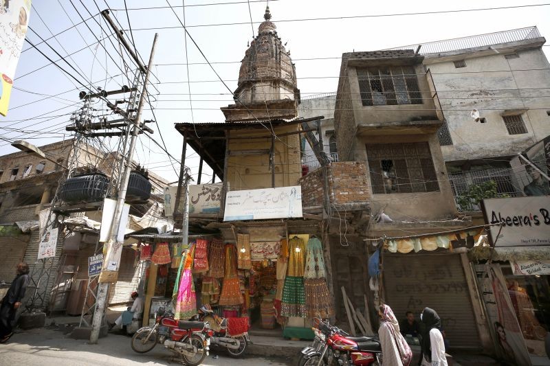 Women walk past a Hindu temple, that was vandalized by a group of assailants, in Rawalpindi, Pakistan on March 29, 2021. Assailants in Pakistan damaged the nearly century-old Hindu temple in the garrison city of Rawalpindi before fleeing the scene. The vandals damaged the door and the stairs of the temple in the attack, which took place on Saturday night, police said. (AP/PTI Photo)