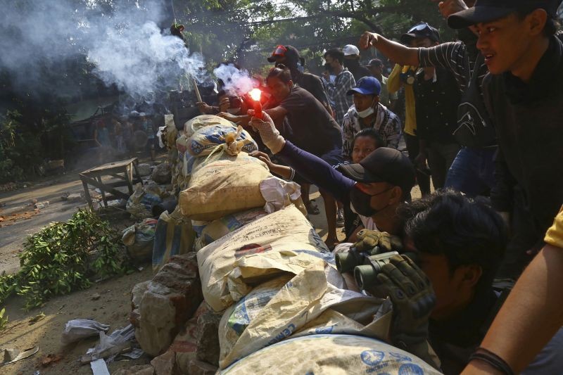 An anti-coup protester holds a smoke bomb behind makeshift barricade, as the protesters confront police in Yangon, Myanmar on March 28, 2021. Protesters in Myanmar returned to the streets Sunday to press their demands for a return to democracy, just a day after security forces killed more than 100 people in the bloodiest day since last month's military coup. (AP/PTI Photo)