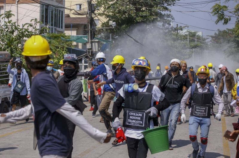 Anti-coup protesters retreat from the frontlines after discharging fire extinguishers towards a line of riot policemen in Yangon, Myanmar on March 10, 2021. (AP Photo)