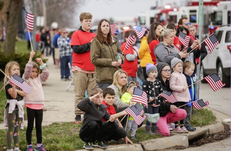 Ely: Community members watch a procession of emergency vehicles in honor of Department of Corrections officer Robert McFarland in Ely, Iowa, Saturday, March 27, 2021. McFarland, a corrections officer at Anamosa State Penitentiary and a lieutenant with the Ely Fire Department, as well as nurse Lorena Schulte were killed by two inmates in the infirmary during an escape attempt. About 12 fire and police agencies including the Iowa Department of Corrections paid tribute to McFarland in the procession past the Ely Fire Department headquarters. AP/PTI
