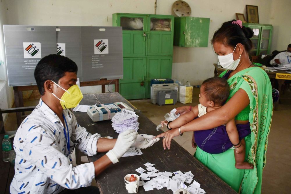 Nagaon: A poll official marks the finger of a voter with indelible ink as she arrives to cast her vote during the first phase of polling for Assam Assembly elections, at Koliabor in Nagaon district, Saturday, March 27, 2021. (PTI Photo)
