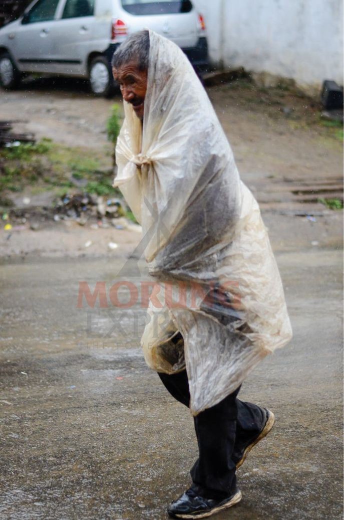 A man uses a plastic sheet to cover himself from the rain as he walks in the road in Tuensang town. (Morung Photo by Moses Hongang Chang) 