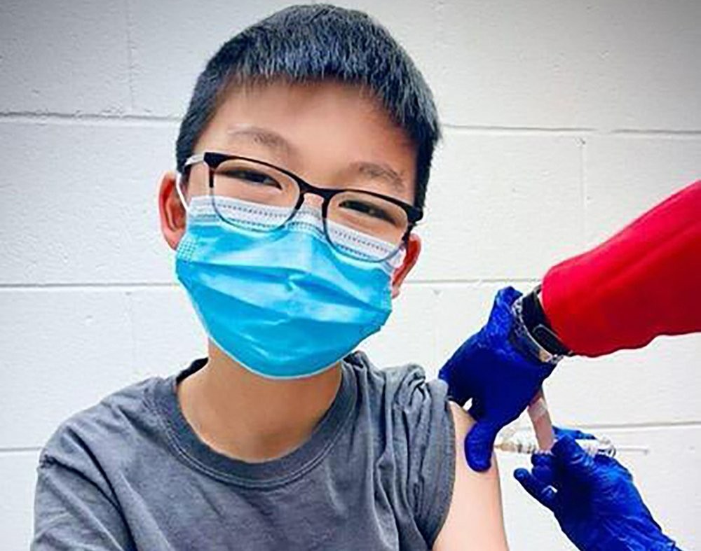 In this Dec. 22, 2020, photo, provided by Richard Chung, his son Caleb Chung receives the first dose of Pfizer coronavirus vaccine or placebo as a trial participant for kids ages 12-15, at Duke University Health System in Durham, N.C. Pfizer says its COVID-19 vaccine is safe and strongly protective in kids as young as 12. The announcement Wednesday, March 31, 2021 marks a step toward possibly beginning shots in this age group before the next school year. (Richard Chung via AP)