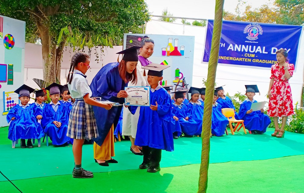 A Kindergarten student receives graduation certificate from his teacher on Monday. (Morung Photo)