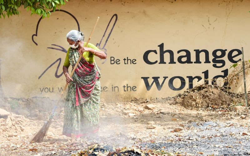 Ahmedabad: A sweeper cleans a road in the backdrop of a wall with a painted slogan, in Ahmedabad, Friday, March 19, 2021. (PTI Photo/Kamal Kishore) 