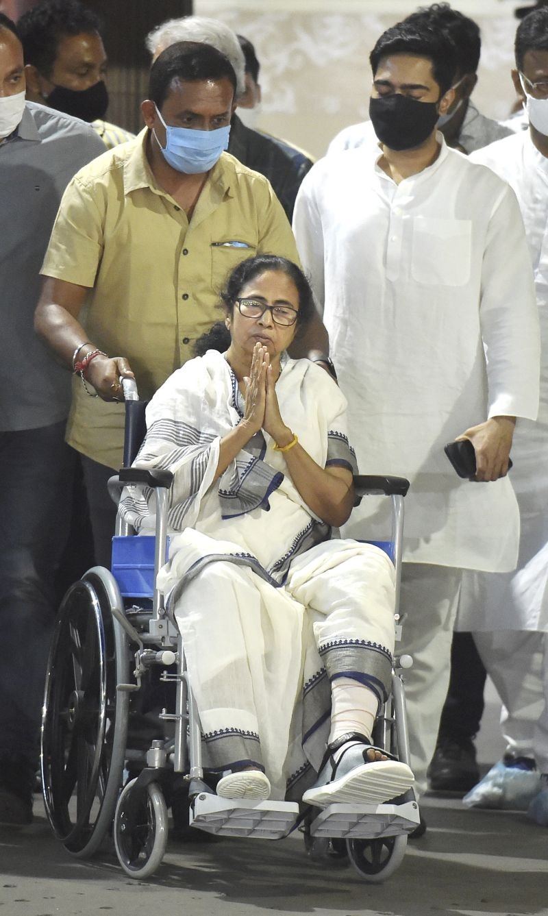 West Bengal Chief Minister Mamata Banerjee greets party activists as she leaves SSKM Hospital in a wheel-chair after being discharged, in Kolkata on March 12. (PTI Photo)