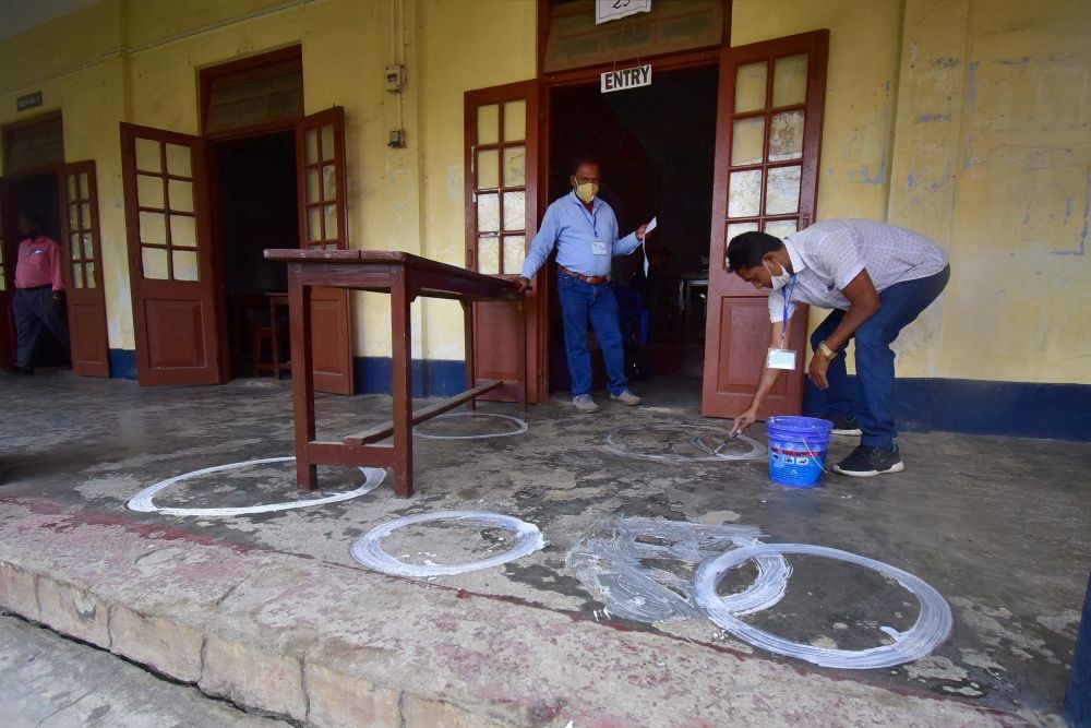 Nagaon: A polling officer draws markers on a floor to ensure social distancing as coronavirus cases spike across the country, on the eve of the second phase of Assam assembly polls, in Nagaon district, Wednesday, March 31, 2021. (PTI Photo)(