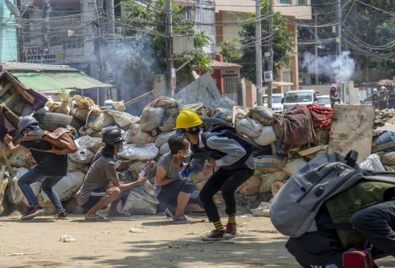 Armed riot policemen charge after firing teargas a rubber bullets as anti-coup protesters abandon their makeshift barricades and run in Yangon, Myanmar on March 16. (AP Photo)
