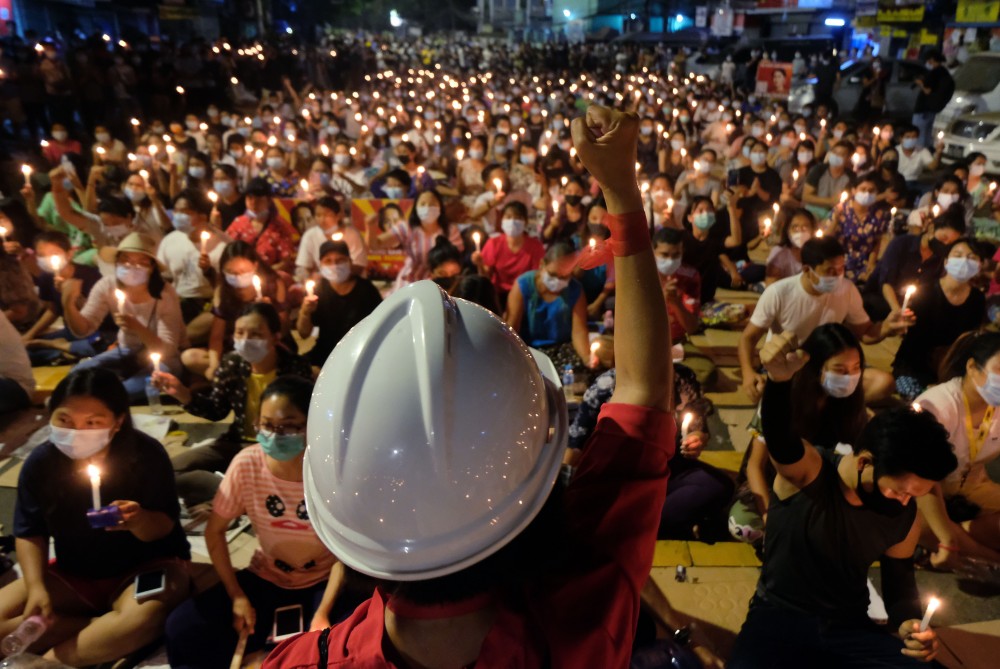 An anti-coup protester raises his hand with clenched fist in front of a crowd during a candlelight night rally in Yangon, Myanmar Sunday, March 14, 2021. (AP/PTI File Photo)