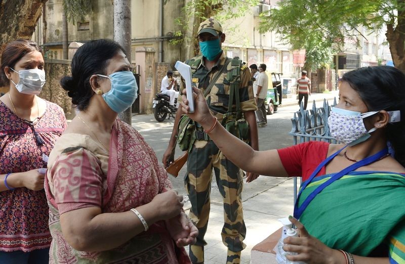 A health worker dooes thermal check at a polling station during the 7th phase of West Bengal State Assembly Elections, in Kolkata on April 261. (PTI Photo)