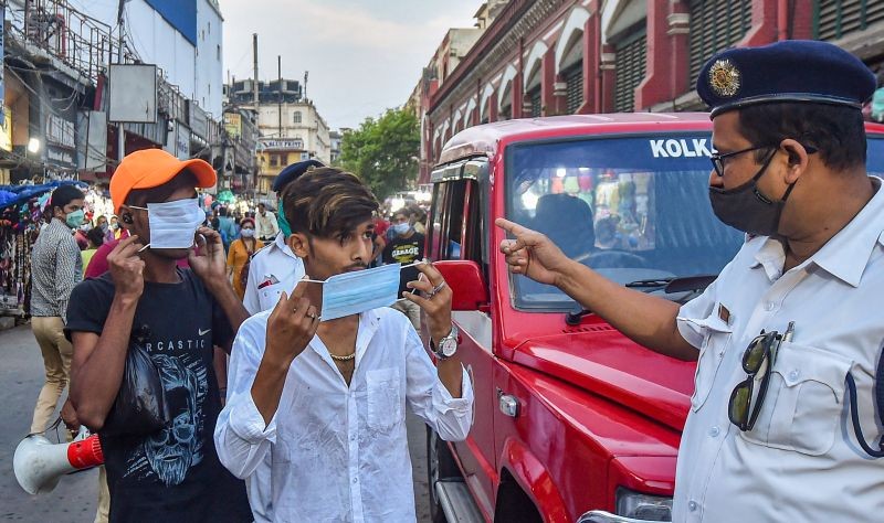A policeman asks people to wear protective face masks, as coronavirus cases surge across the country, at New Market area of Kolkata on April 14, 2021. (PTI Photo)