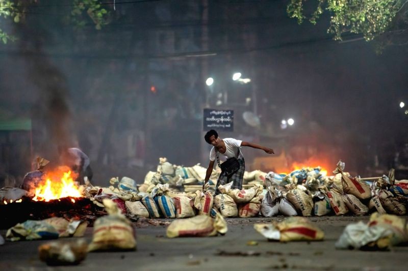 A demonstrator stacks bags on a street as a barricade during a demonstration against the military coup and the detention of civilian leaders. (IANS Photo)