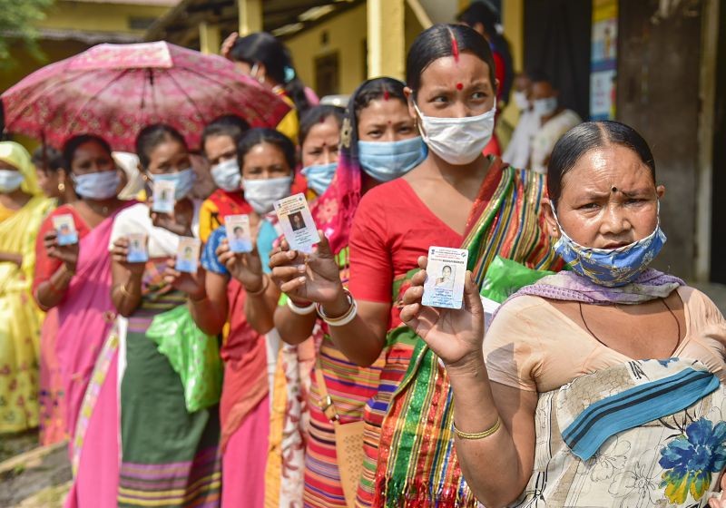 Hajong tribal women show their voter identity cards as they wait in the queue to cast their votes at a polling Station for Assembly polls, at Boko in Kamrup district on  April 6, 2021. (PTI Photo)