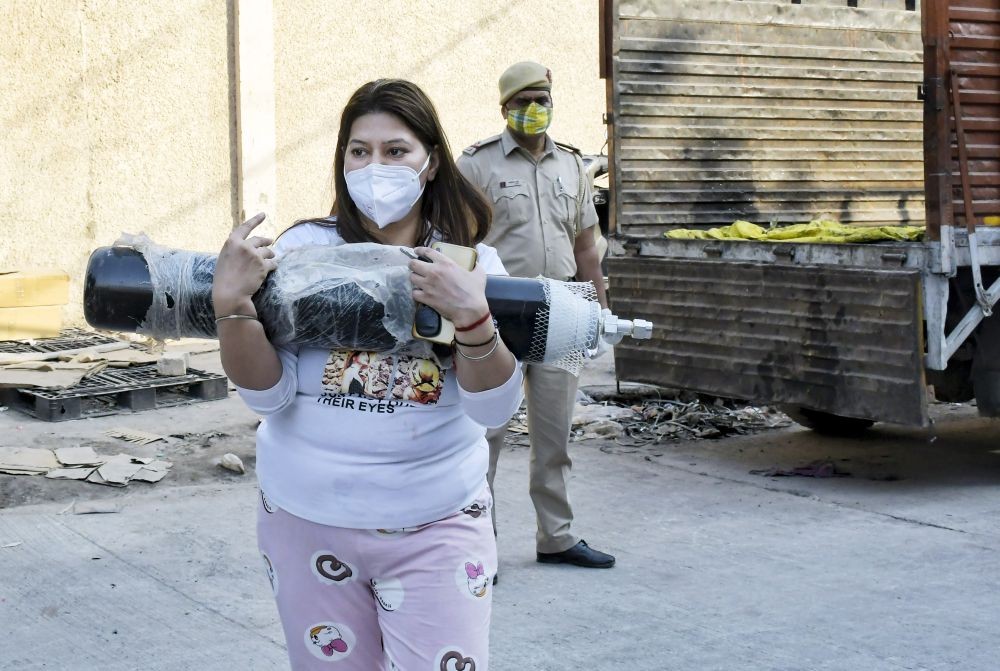 New Delhi: A family member of a COVID-19 patient carries an oxygen cylinder for refilling outside a filling center at Mayapuri, as demand for the gas rises due to spike in coronovirus cases, in New Delhi, Thursday, April 22, 2021. (PTI Photo)